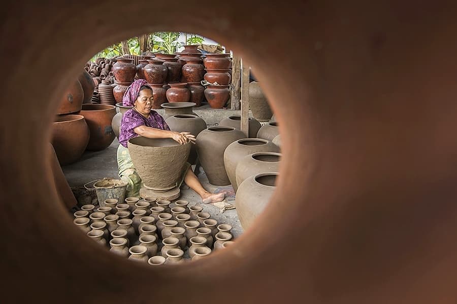Traditional Sasak village with thatched roof houses and local artisans working on pottery